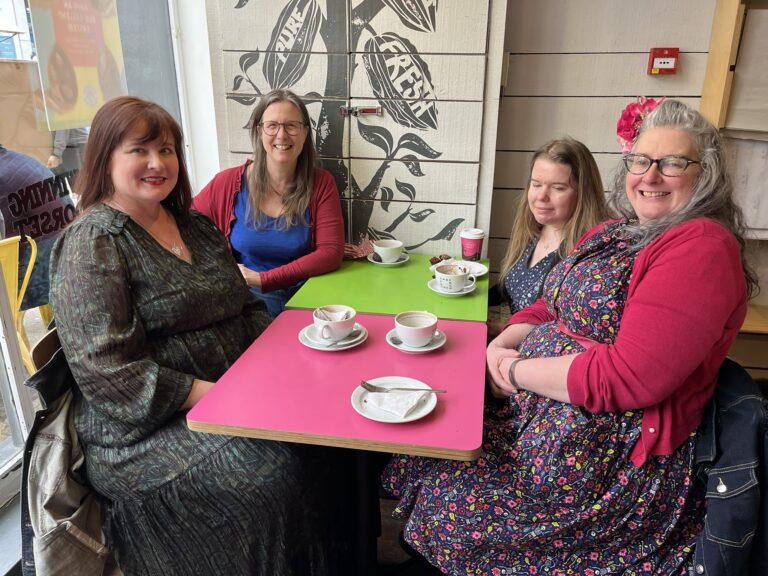 Taking online friendships offline. Smiley colourful picture of four women around a table at a café. They're enjoying hot chocolate at Chococo!